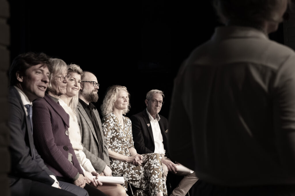 De deelnemende policiti zitten op een rij terwijl ze wachten op hun beurt om te debatteren.